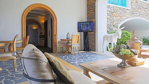 A cozy lobby with a sofa, a wooden table, a TV, and a stone wall. - Chelona Khaotao Hua Hin E702 (Hua Hin)