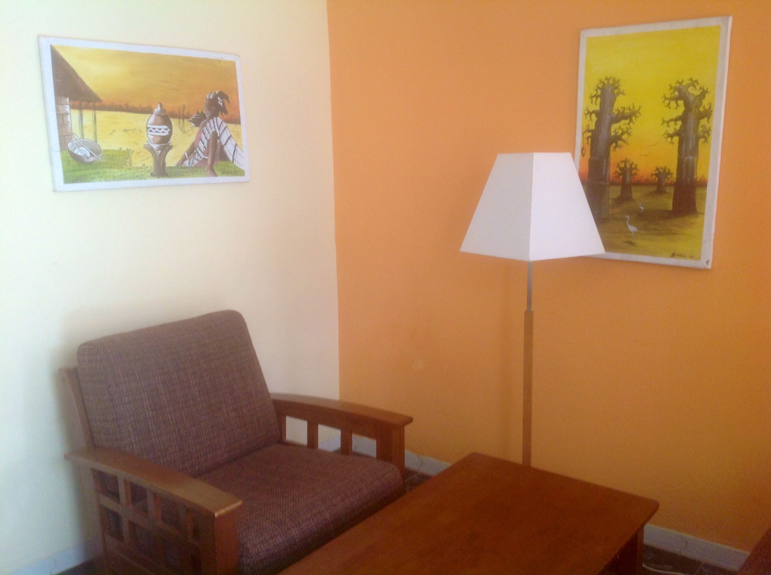 Una habitación con un sofá, una mesita y dos cuadros en la pared.