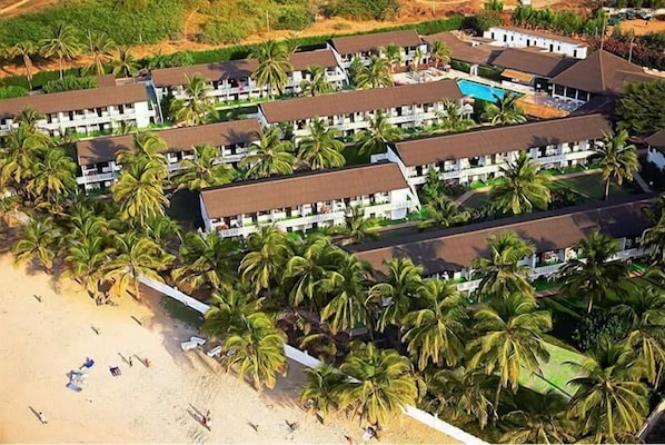 A resort with multiple bungalow-style buildings, a beach, and palm trees. - Bungalow Beach Hotel (Serrekunda)