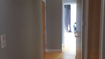 A hallway with wooden flooring, grey walls, and a ceiling with recessed lighting.