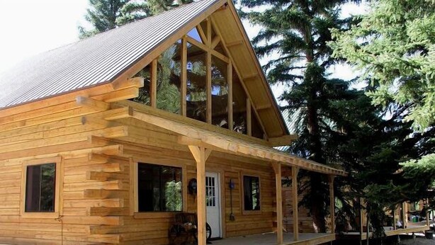 A wooden cabin with a gabled roof, a front porch, and a small front yard. - Texan Resort (Lake City)