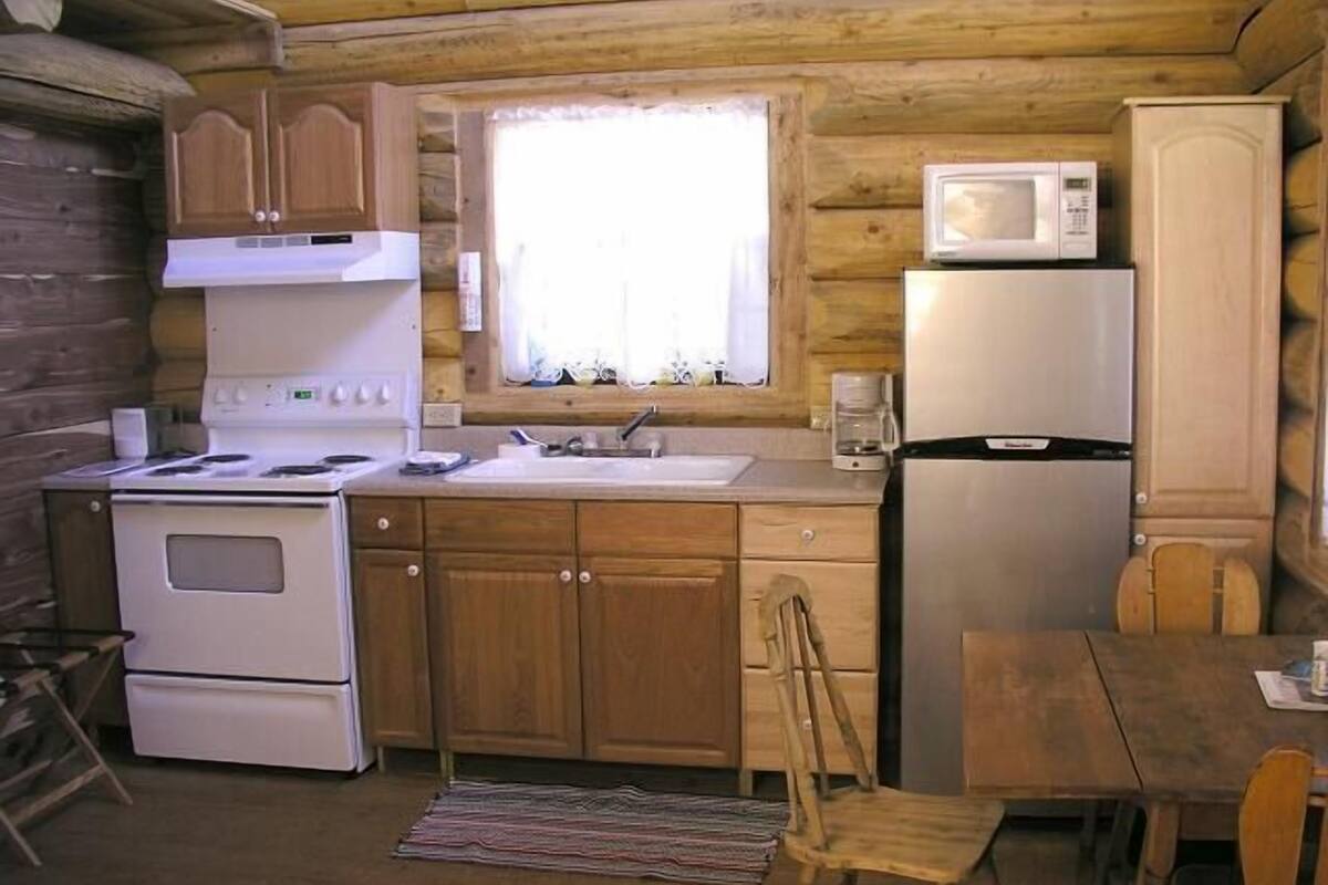 Una cocina compacta con armarios de madera, estufa, microondas y refrigerador.