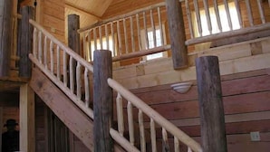 A wooden staircase with a handrail, leading to an upper level. - Texan Resort (Lake City)