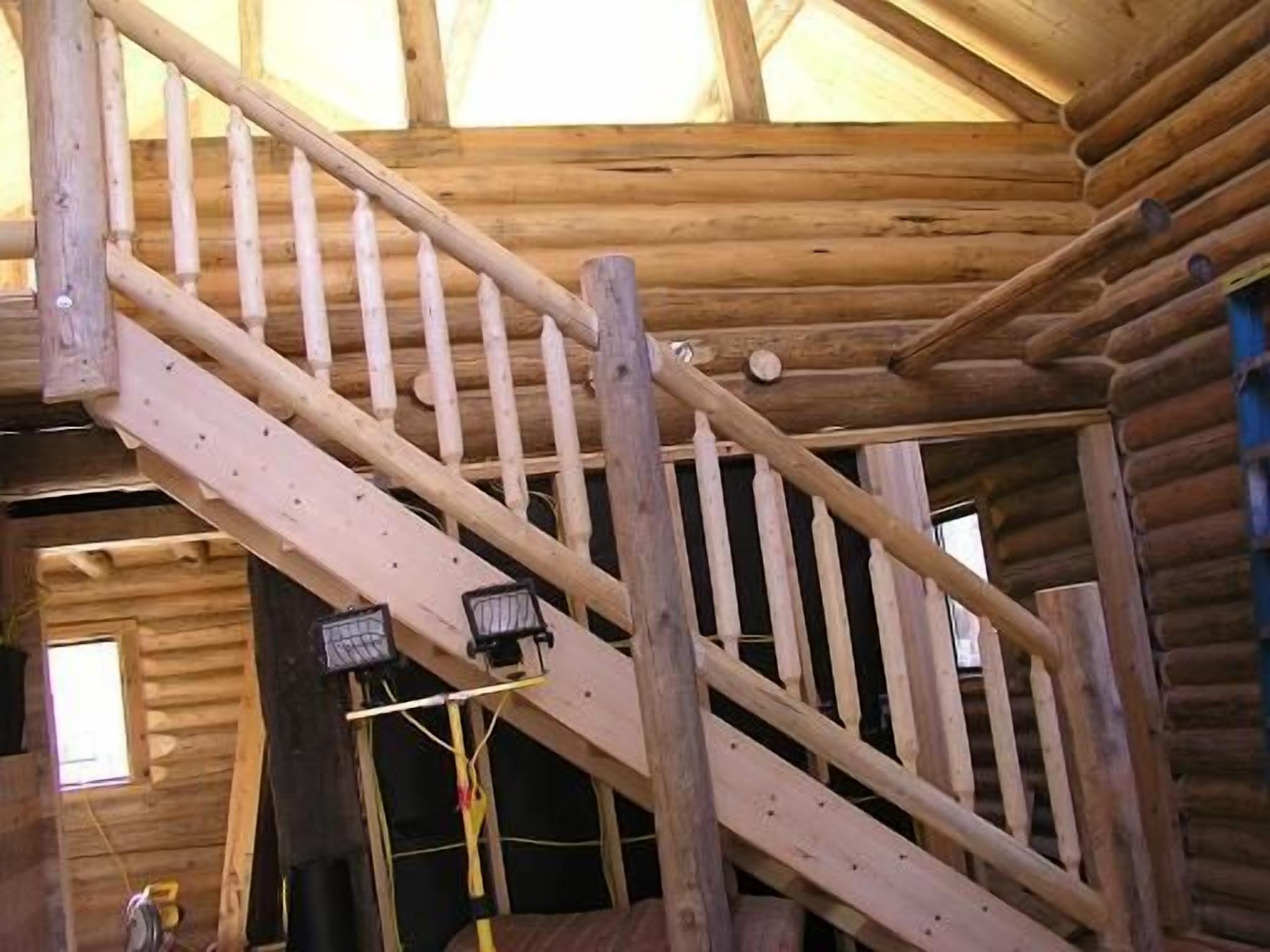 A wooden staircase with a handrail, wooden walls, and a window.