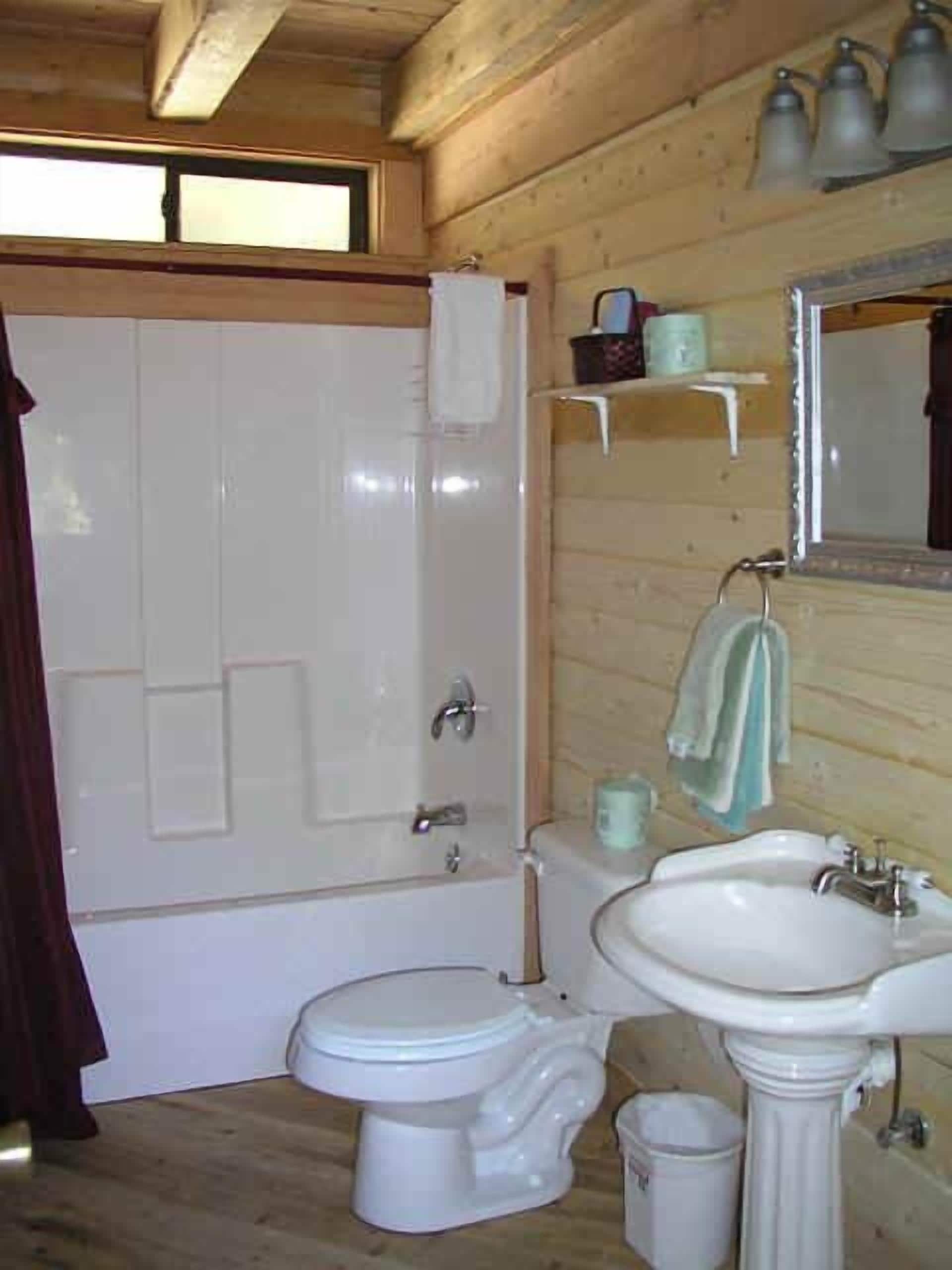 A bathroom with a bathtub, toilet, sink, and a mirror.