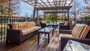 Una terraza techada al aire libre con mobiliario de mimbre y mesas de vidrio.
