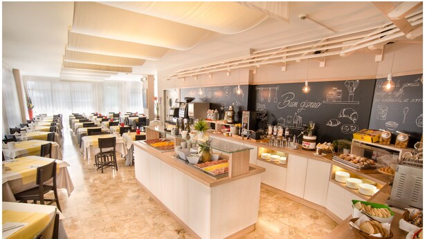 A restaurant with a central bar area, multiple seating tables, and a chalkboard menu.