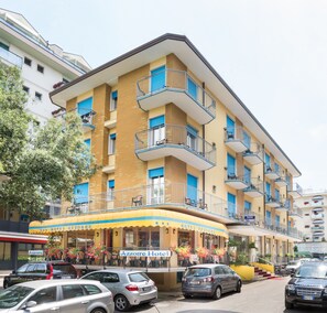 A multi-story hotel with balconies, a yellow awning, and a sign reading "Hotel Azzorre".