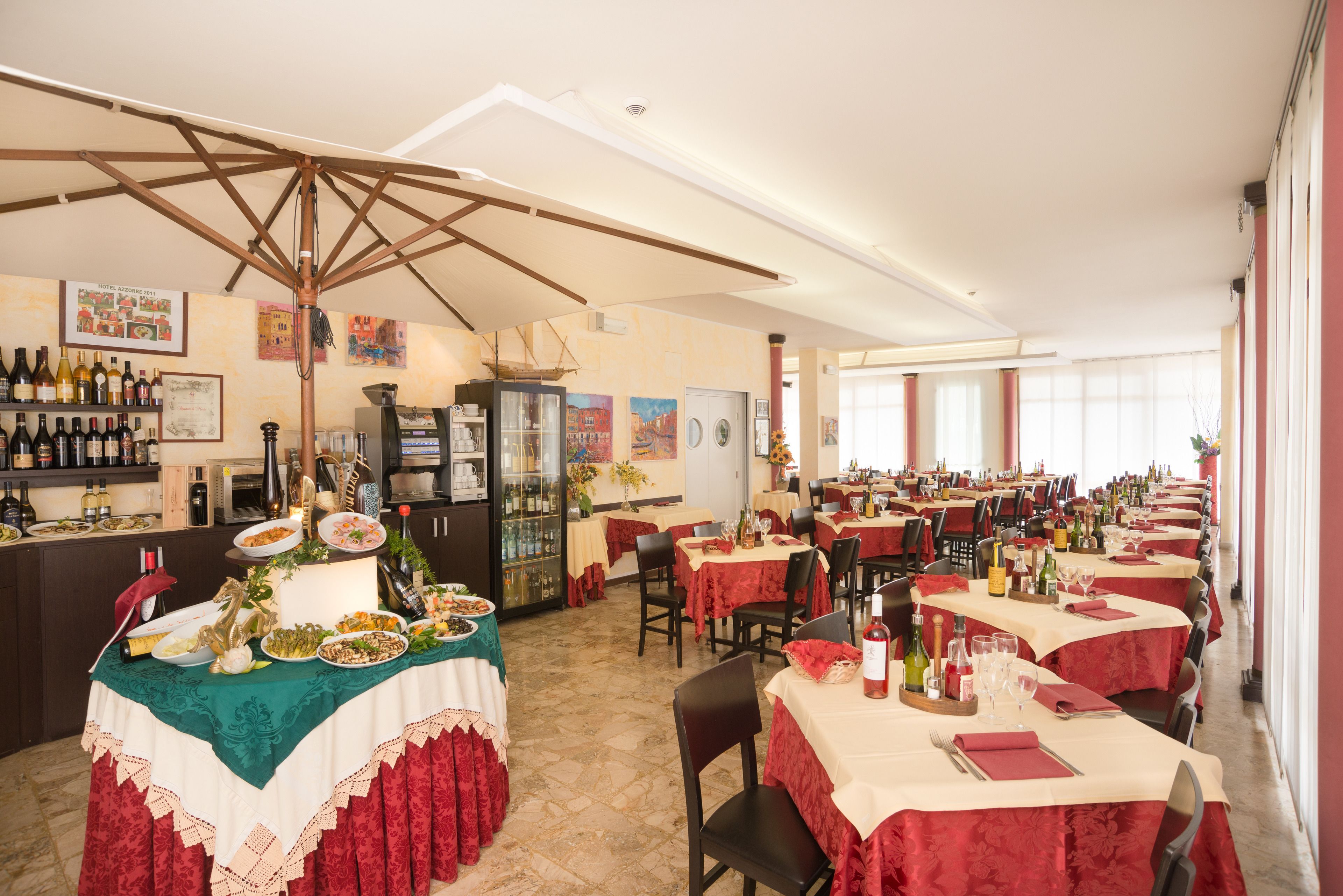 A restaurant with multiple tables, a bar area, and various food and drink items displayed.