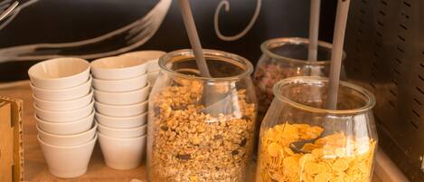 Ein Tisch mit Schüsseln, Granola- und Cereal-Gläsern, einem Kuchen und einem Waffeleisen.