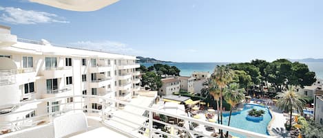 Un hotel con zona de piscina, mobiliario exterior y vistas al mar.