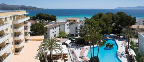 A resort with a large swimming pool, multiple balconies, and a view of the sea.