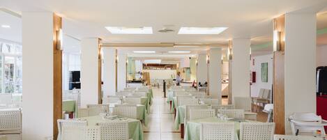 Un restaurant spacieux avec de hauts plafonds, de nombreuses tables et des chaises disposées pour accueillir les clients.