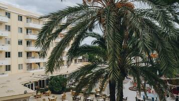 A hotel courtyard with outdoor seating, palm trees, and a multi-story building with balconies.