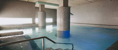 Une piscine intérieure avec des murs carrelés et un plafond transparent.