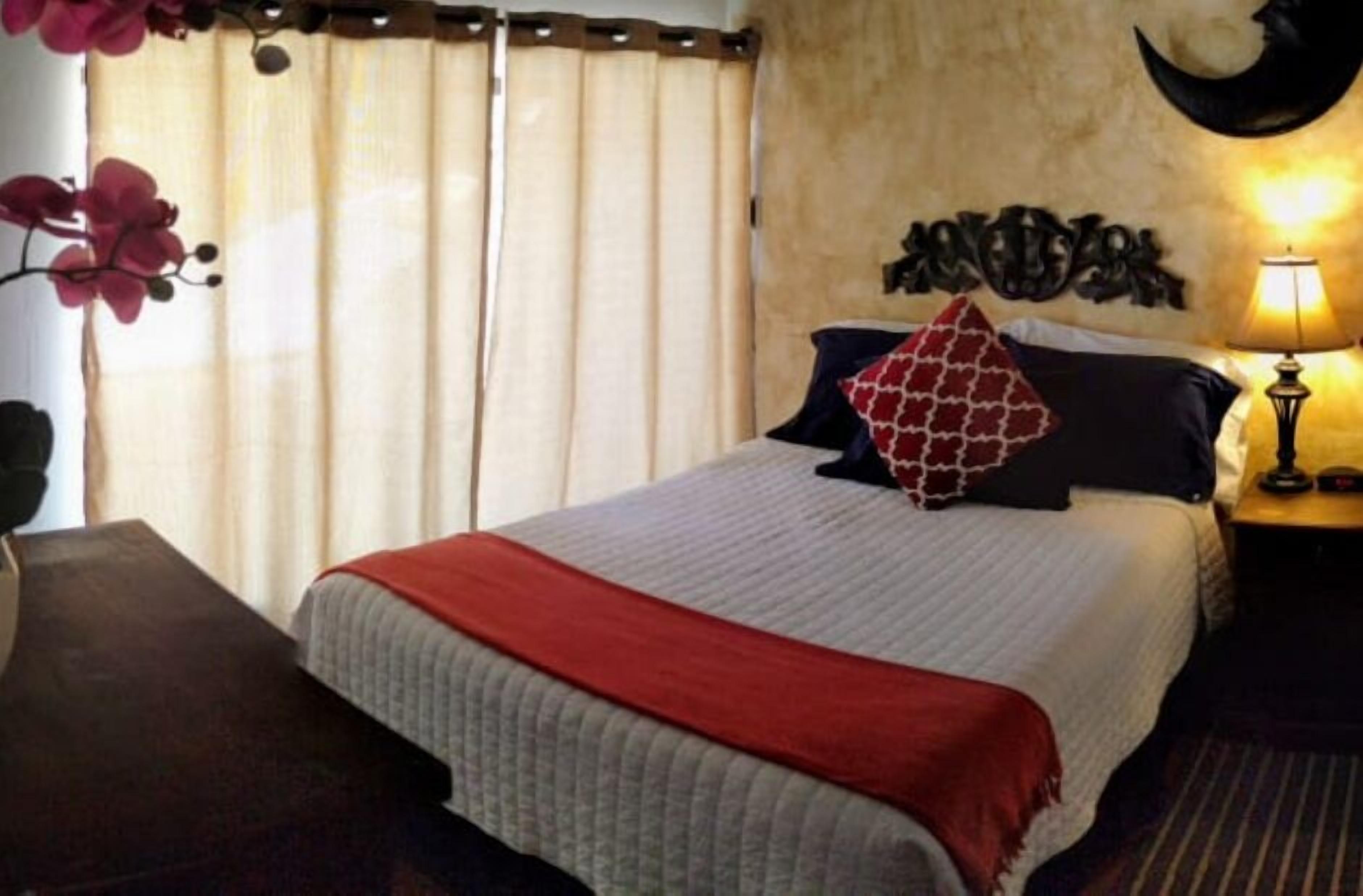 Una habitación de hotel con cama, mesita de noche, lámpara y decoración en la pared.