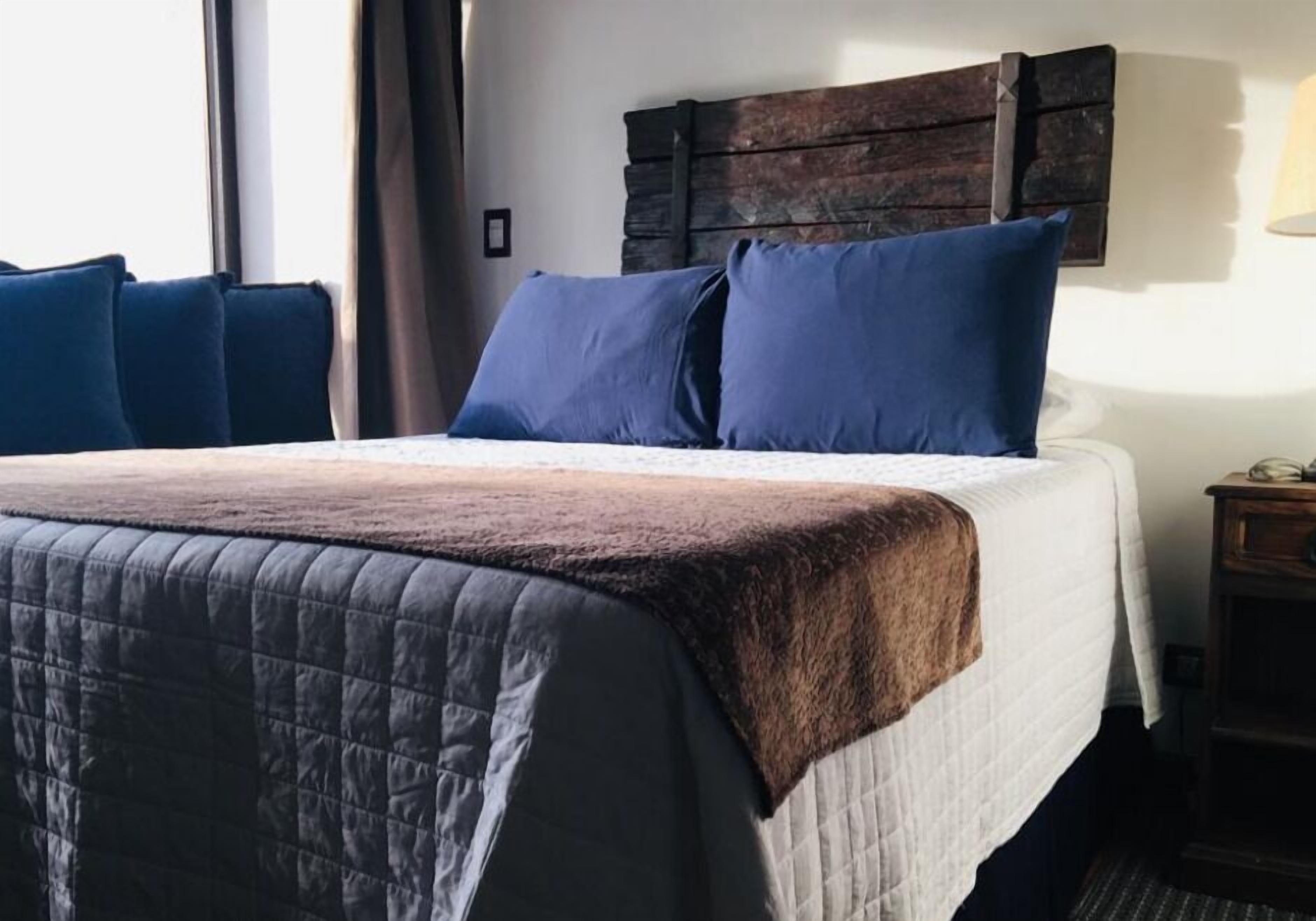 A bed with a quilted cover, two pillows, and a wooden headboard.
