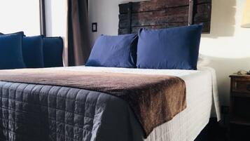 A bed with a quilted cover, two pillows, and a wooden headboard.