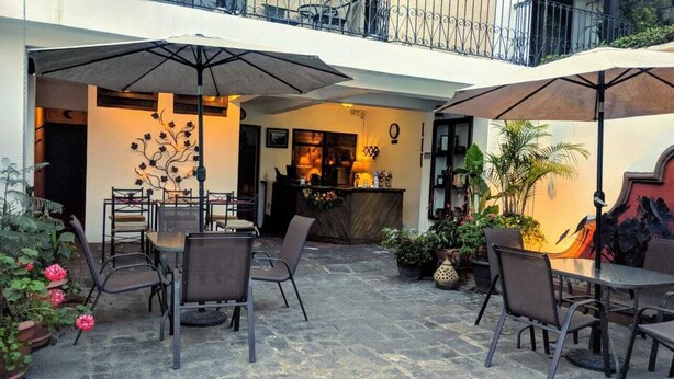 Un patio al aire libre con mesas, sillas, sombrillas y plantas en macetas.