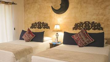 A hotel room with two beds, a nightstand with a lamp, and a crescent moon decoration on the wall.