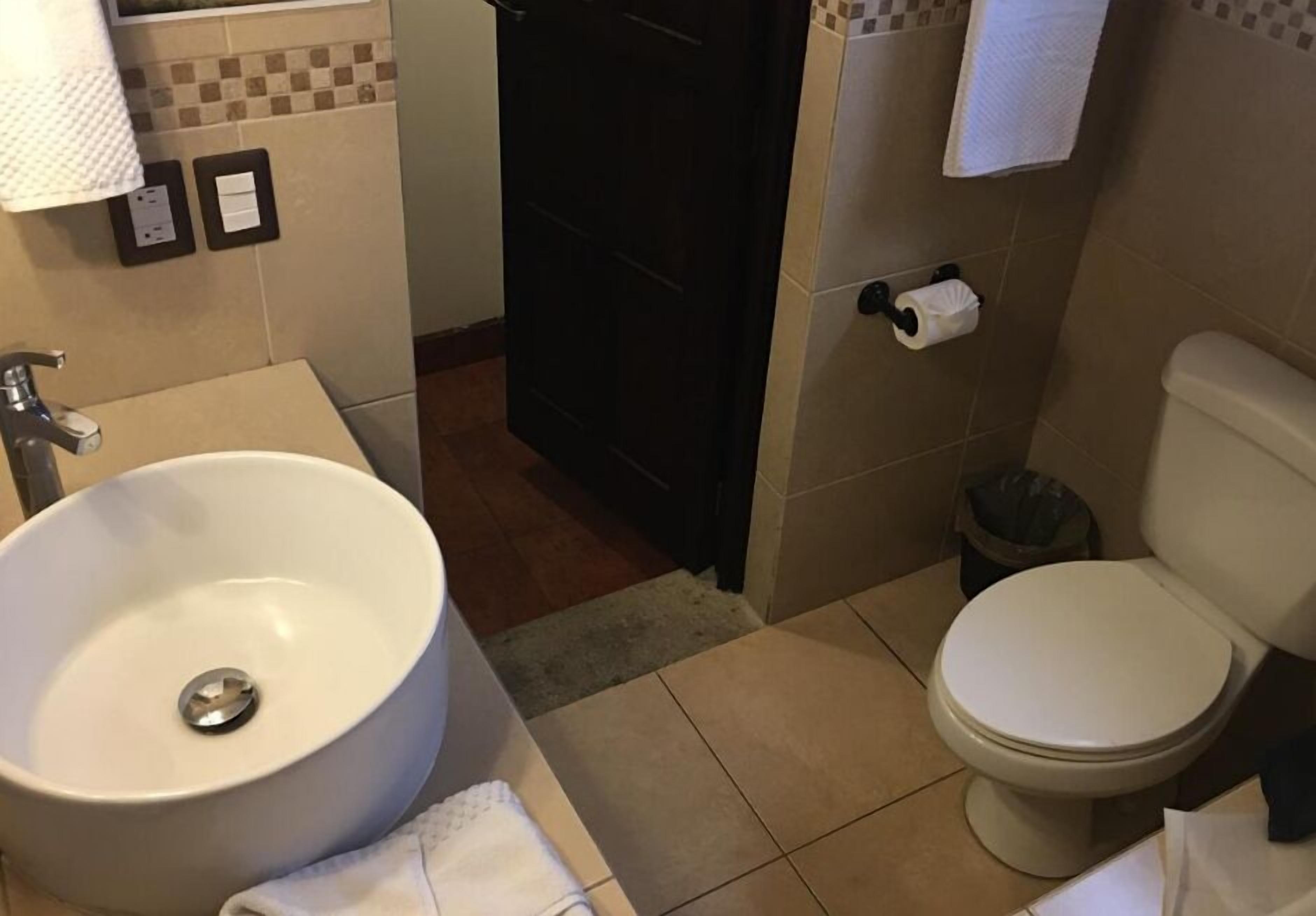Un baño con lavamanos blanco, inodoro y toallero.