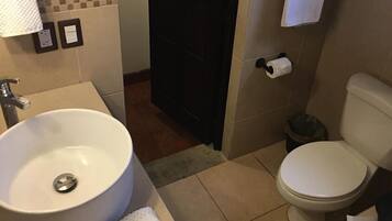 Un baño con lavamanos blanco, inodoro y toallero.
