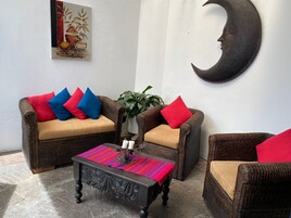 Una sala de estar acogedora con muebles de mimbre, una mesa de centro y una decoración en forma de luna creciente en la pared.