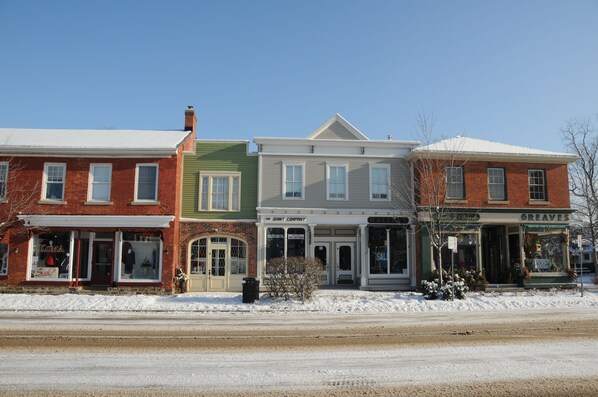 A row of brick buildings with storefronts, including a visible sign for 'The Shiny Company'. - Greaves Sweet Escape (Niagara-on-the-Lake)