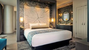 A modern hotel room with a large bed, a round mirror, a vanity, and a wardrobe. - Wind Creek Casino & Hotel Wetumpka (Wetumpka)