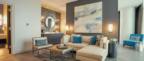 A modern living room with a sofa, armchairs, a coffee table, and a large abstract painting on the wall.