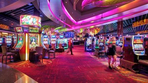 A casino with slot machines, a red carpet, and a modern ceiling design.