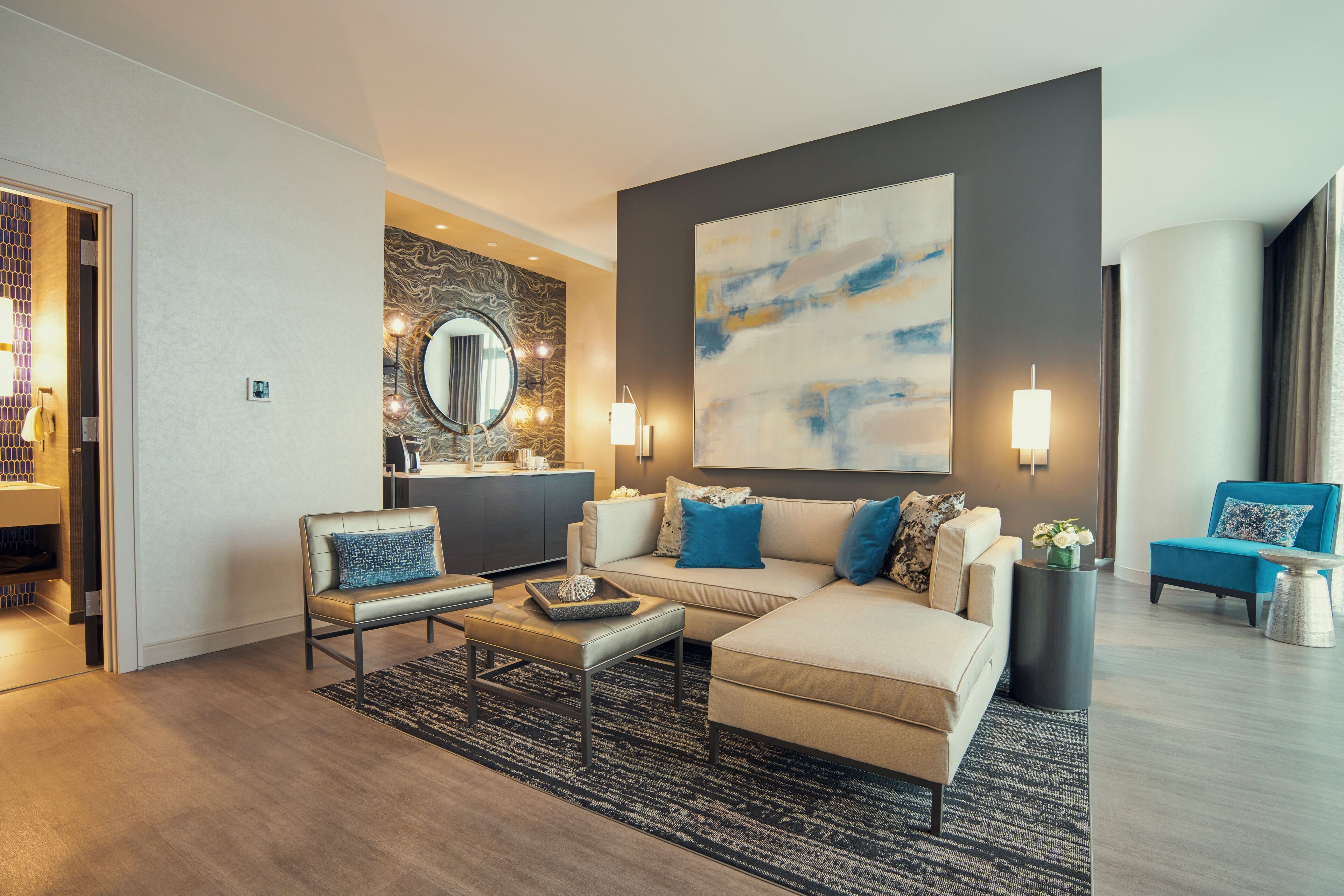 Een moderne woonkamer met een bank, salontafel en een groot abstract schilderij aan de muur.