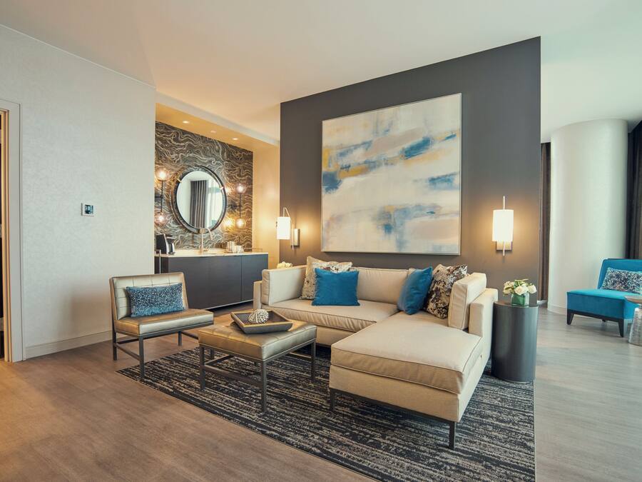 Een moderne woonkamer met een bank, salontafel en een groot abstract schilderij aan de muur.