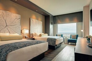 A hotel room with two beds, a sitting area, a large window, and artwork on the walls. - Wind Creek Casino & Hotel Wetumpka (Wetumpka)