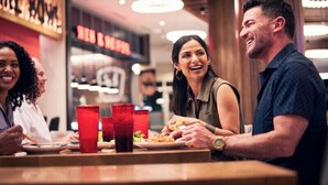 A group of people dining at a restaurant with a modern interior and a visible menu sign.