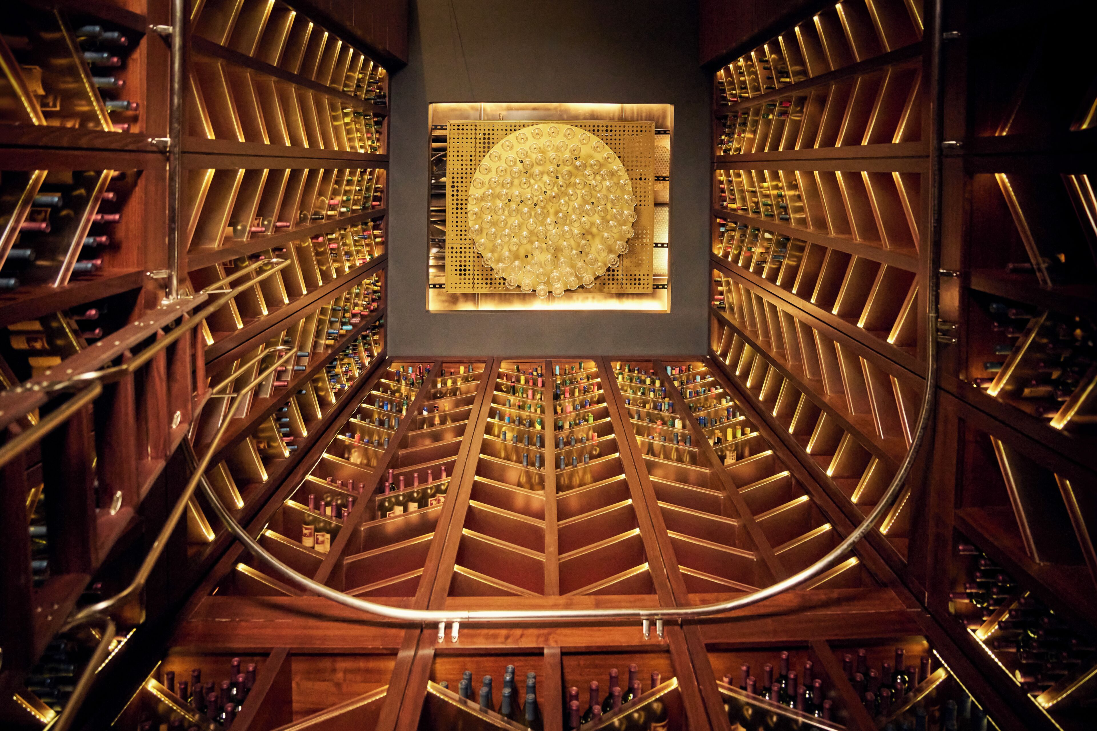 A wine cellar with wooden racks and a central illuminated structure.