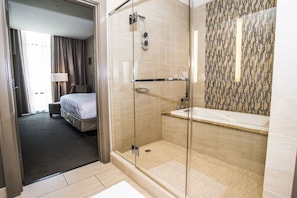 Een hotelbadkamer met een douche in een glazen cabine, een witte badkuip en een betegelde douchecel.