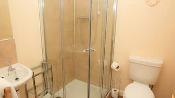 Un baño con cabina de ducha de vidrio, un lavamanos blanco y un inodoro.
