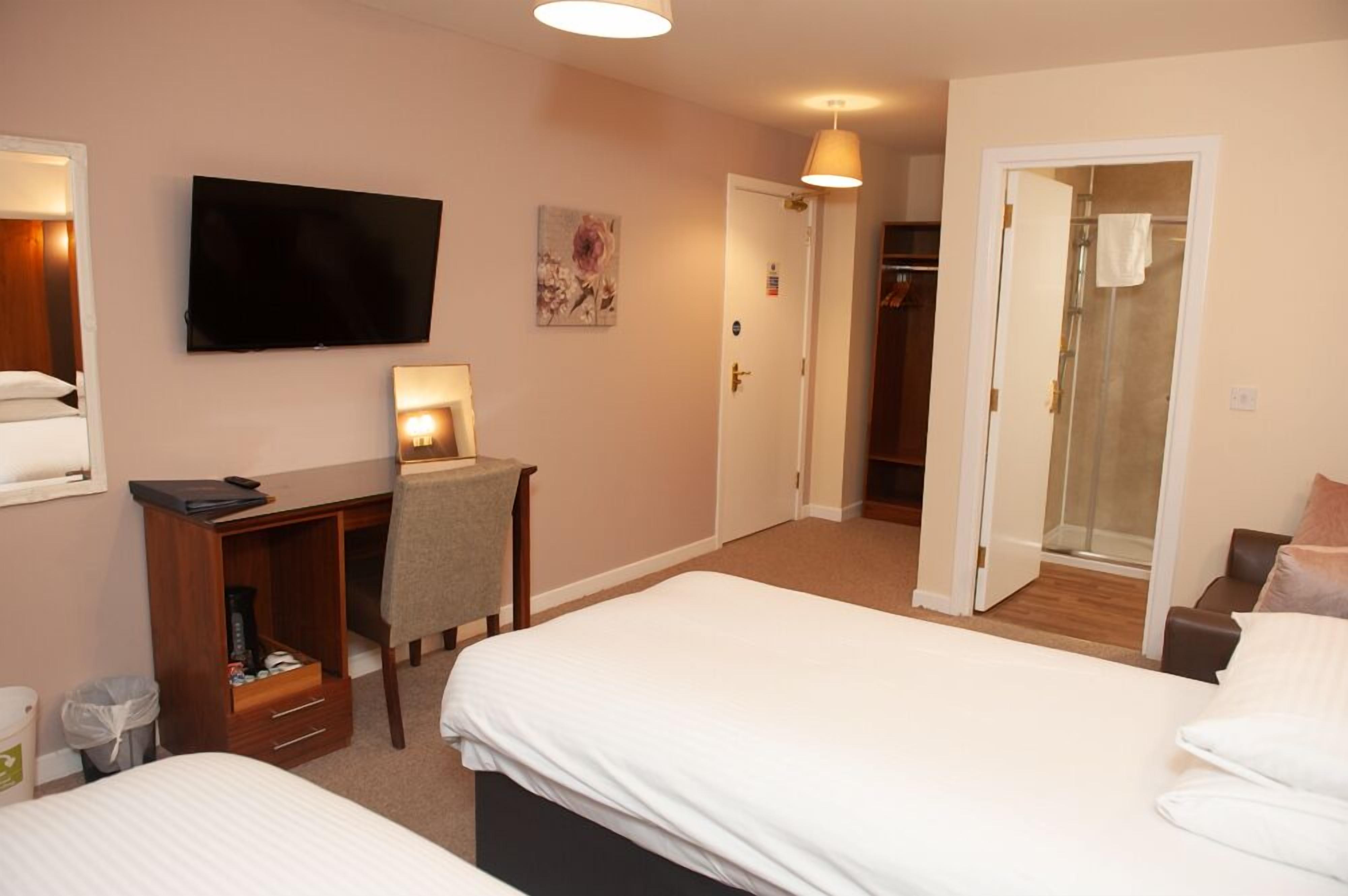 Une chambre d’hôtel comprenant un lit, un bureau avec une chaise, une télévision et un espace douche.