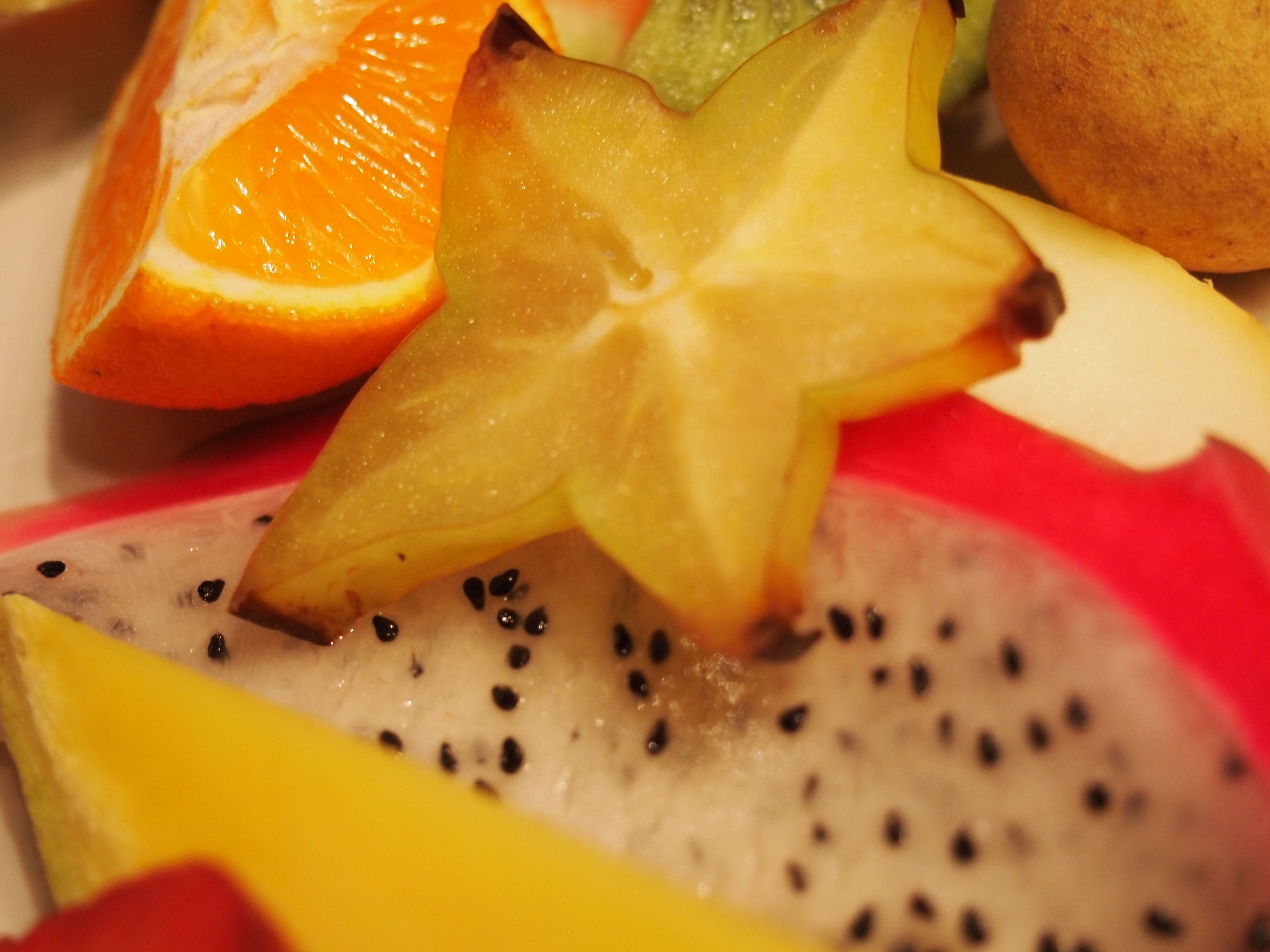 A close-up of a fruit arrangement with a star-shaped fruit, orange, and dragon fruit slices.