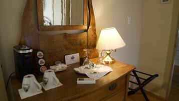 A wooden dresser with a mirror, a lamp, a coffee maker, and a tea set.