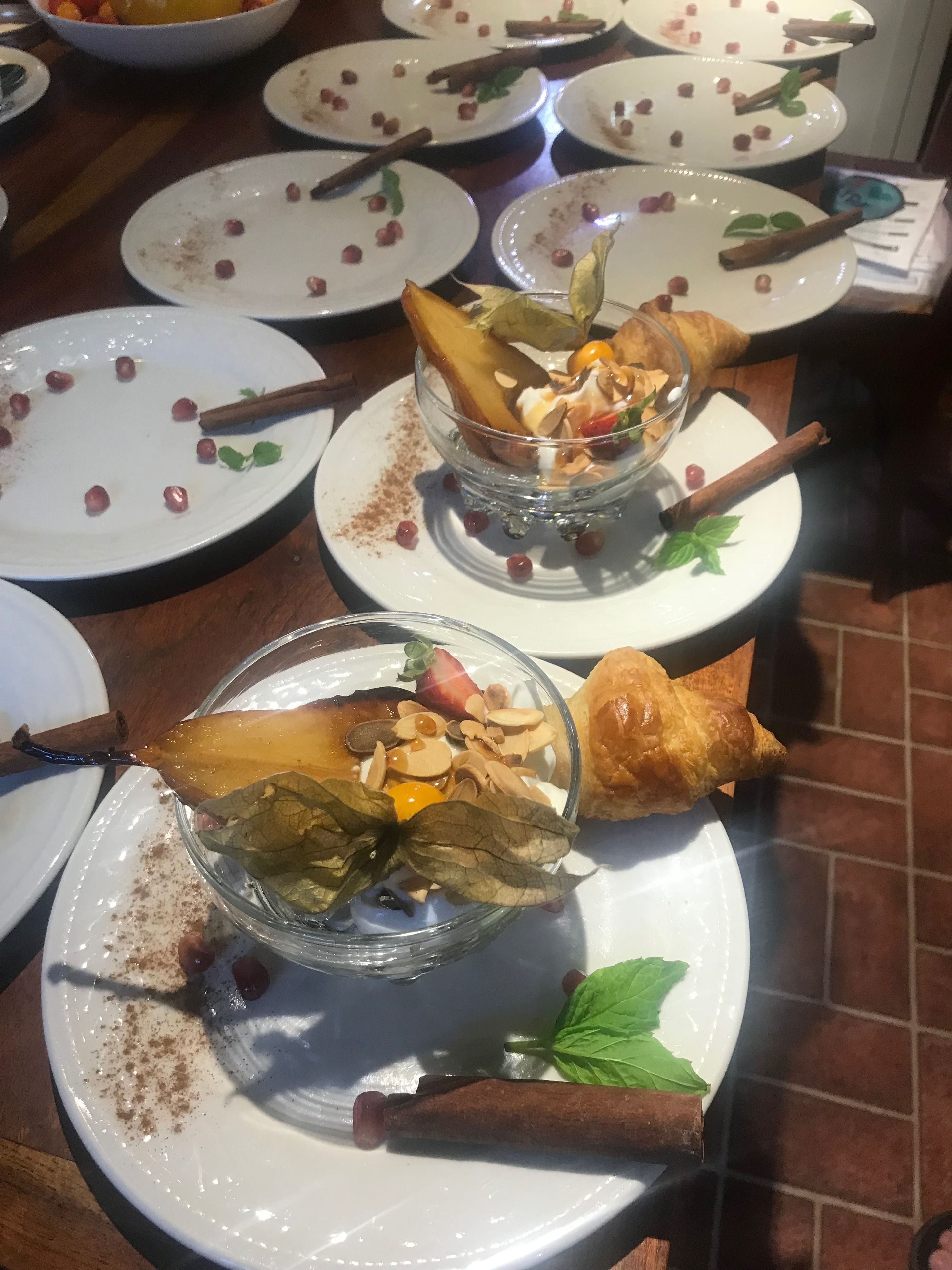 A dining table with multiple plates, some with food remnants and cinnamon sticks.
