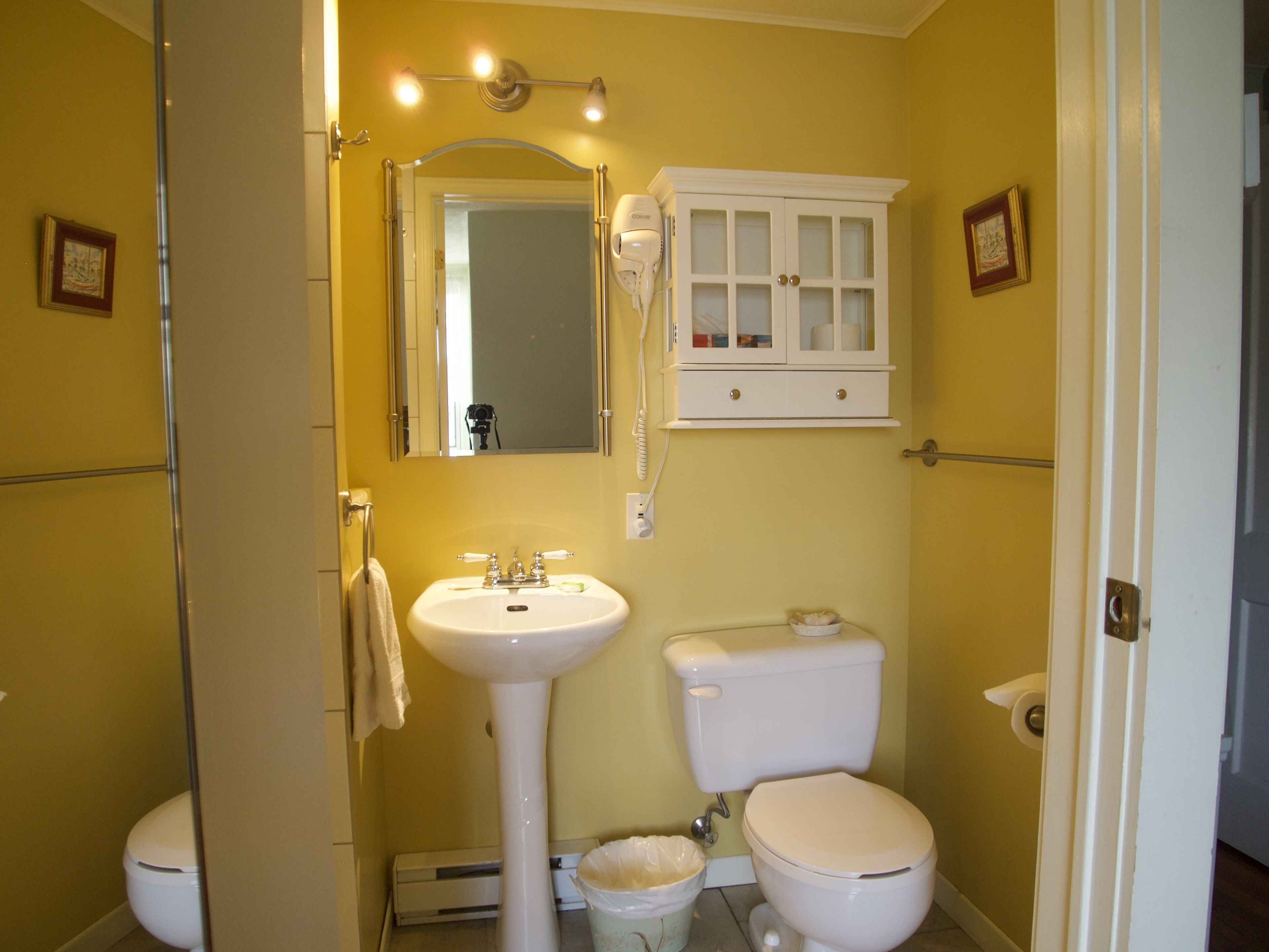 A bathroom with a white sink, toilet, and vanity cabinet.