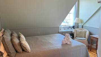 A bedroom with a large bed, a desk, a chair, and a window.