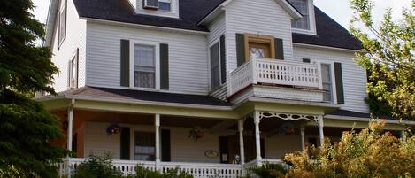 A two-story house with a balcony, a front porch, and a chimney.
