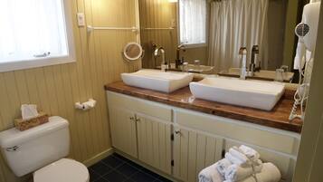 A bathroom with two sinks, a toilet, a mirror, and a towel rack.