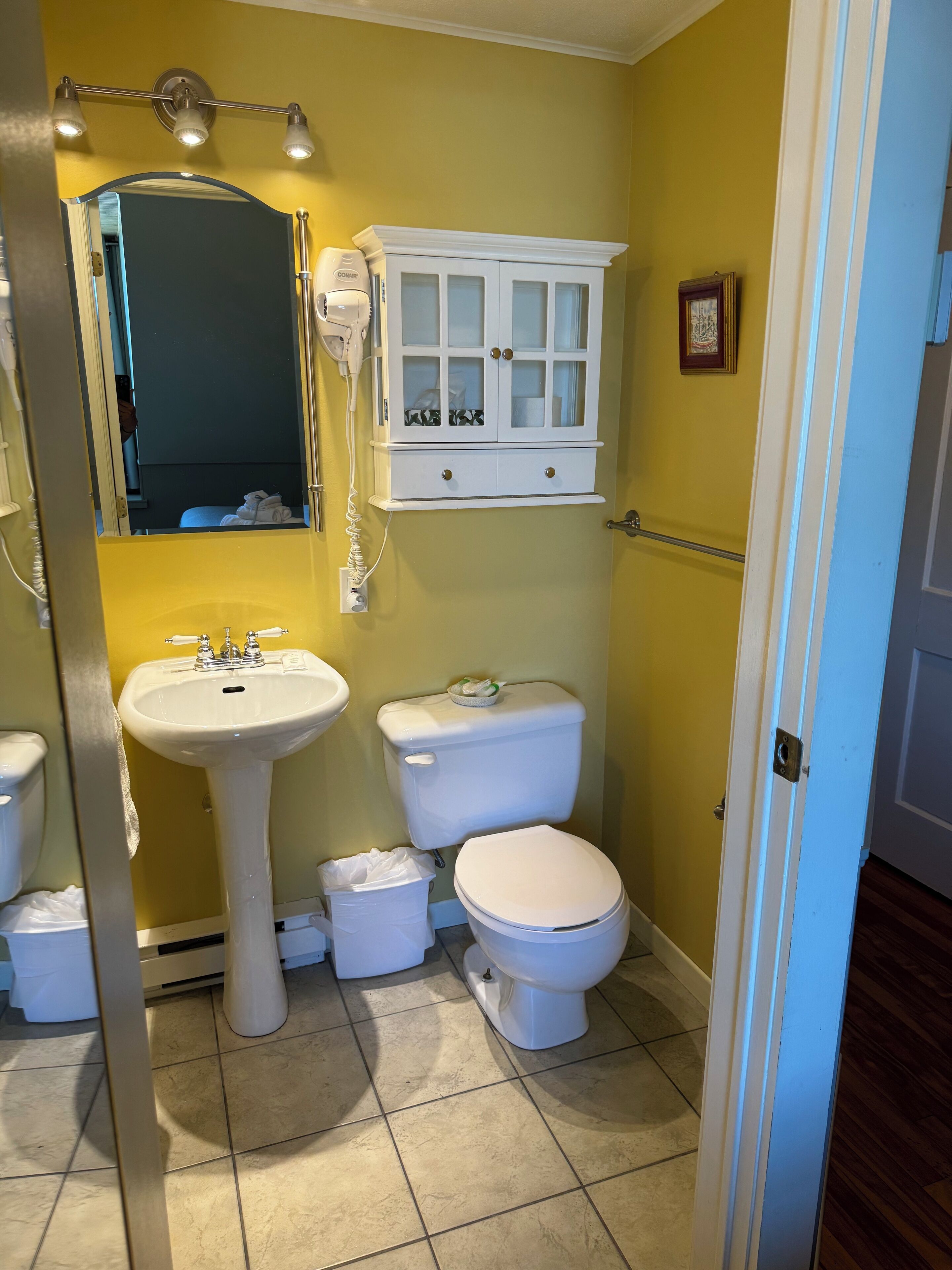 A bathroom with a sink, toilet, and cabinet.