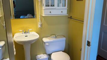 A bathroom with a sink, toilet, and cabinet.