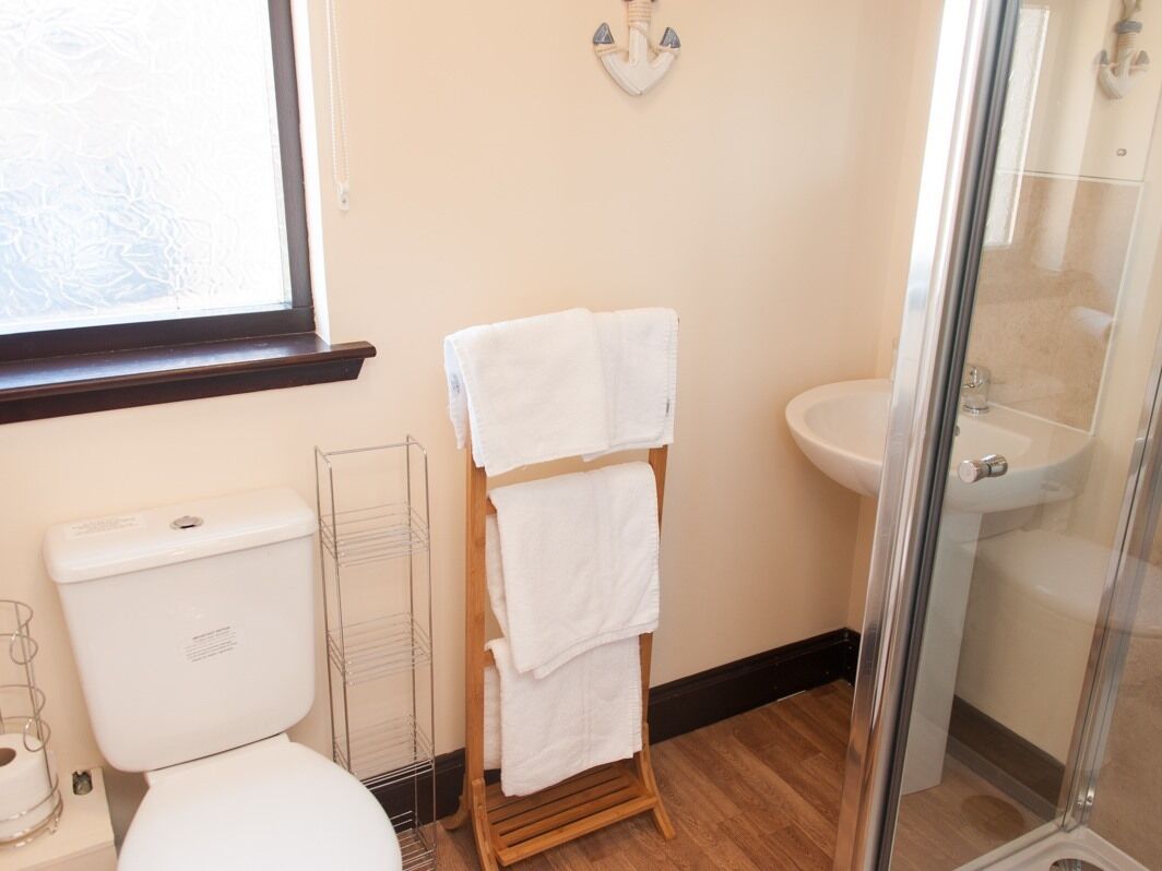 Un baño con inodoro, lavamanos y cabina de ducha de vidrio.