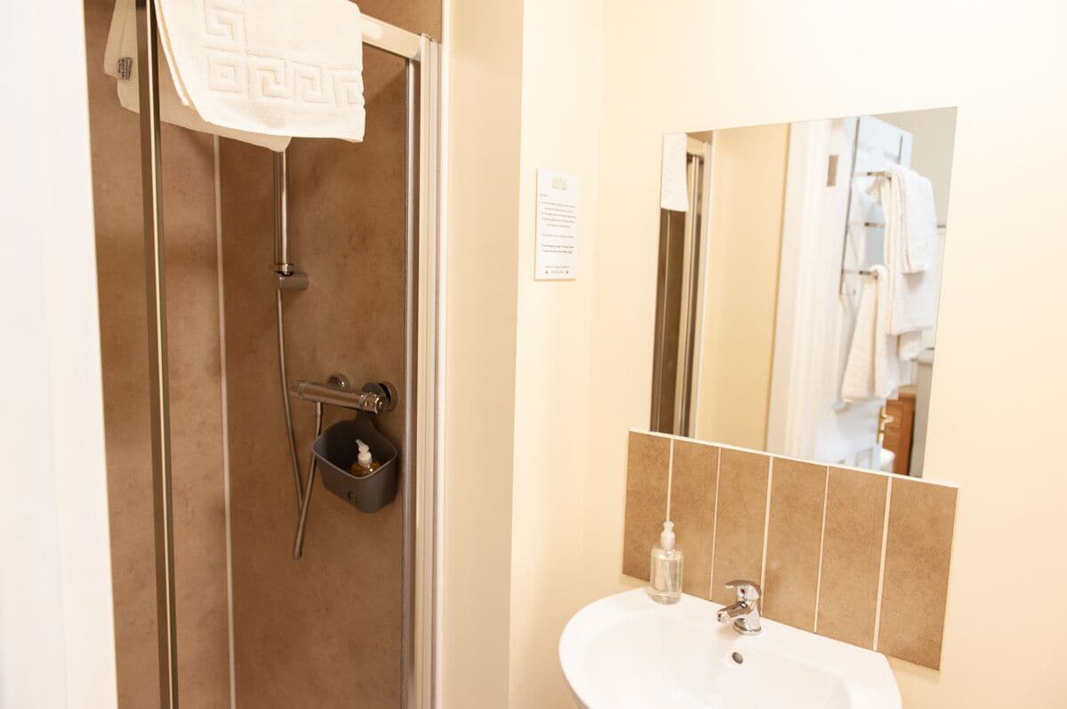 A bathroom with a shower, a sink, and a mirror.